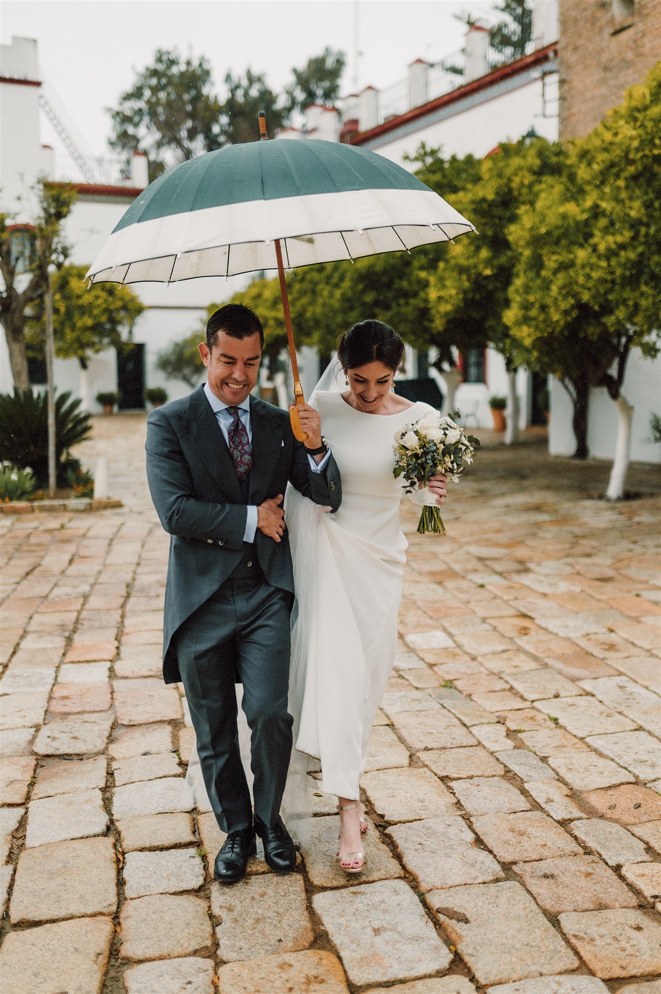 Pareja de novios con paraguas en una boda con lluvia en Sevilla